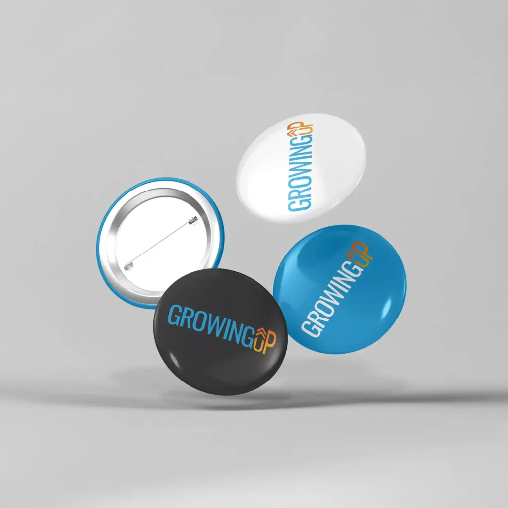 MOCKUP : 3 pin's, 1 blanc, 1 bleu et 1 noir, ornés du logo de l'organisme de formation GrowingUp